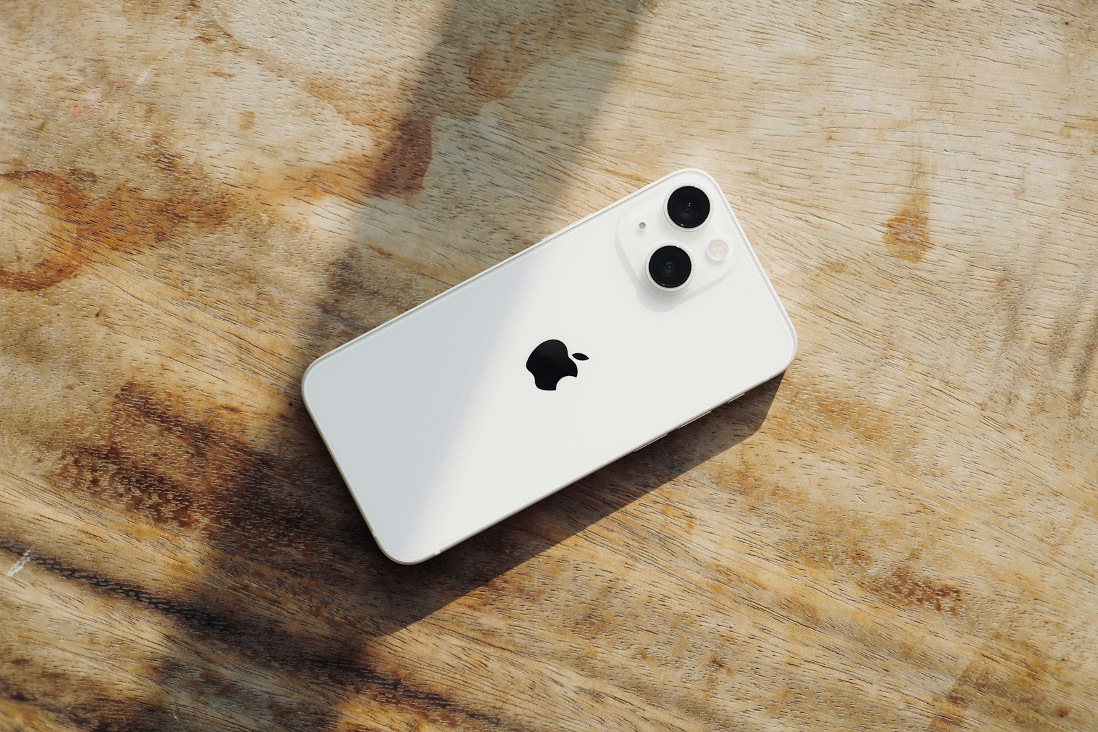 a white iphone sitting on top of a wooden table